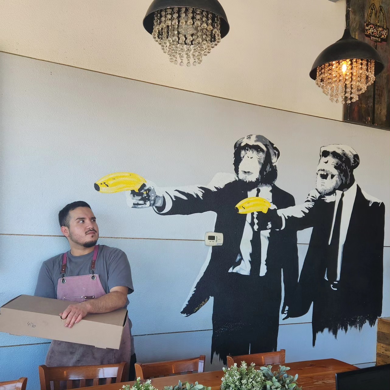 Madhouse Coffee team member beside the shop mural